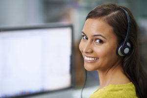 Shot of an attractive female with headsets on smiling while looking over her shoulder at work
